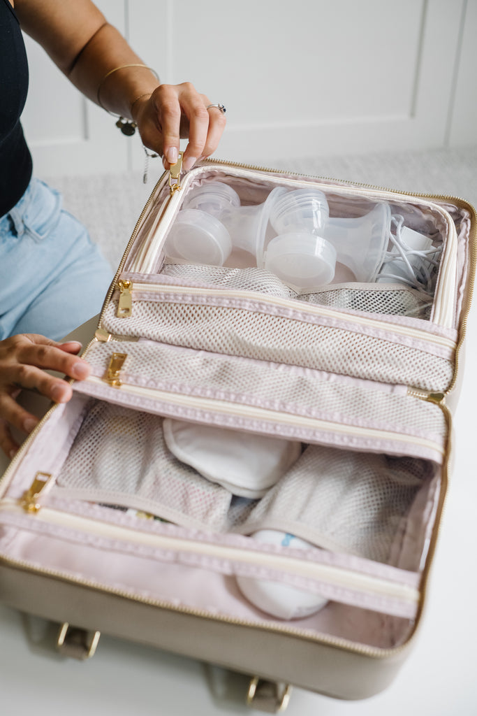 An open vegan leather breast pump organizer with neatly arranged compartments holding breast pump parts and accessories, including flanges and tubing, showcasing its efficient design for keeping items organized and ready to use.